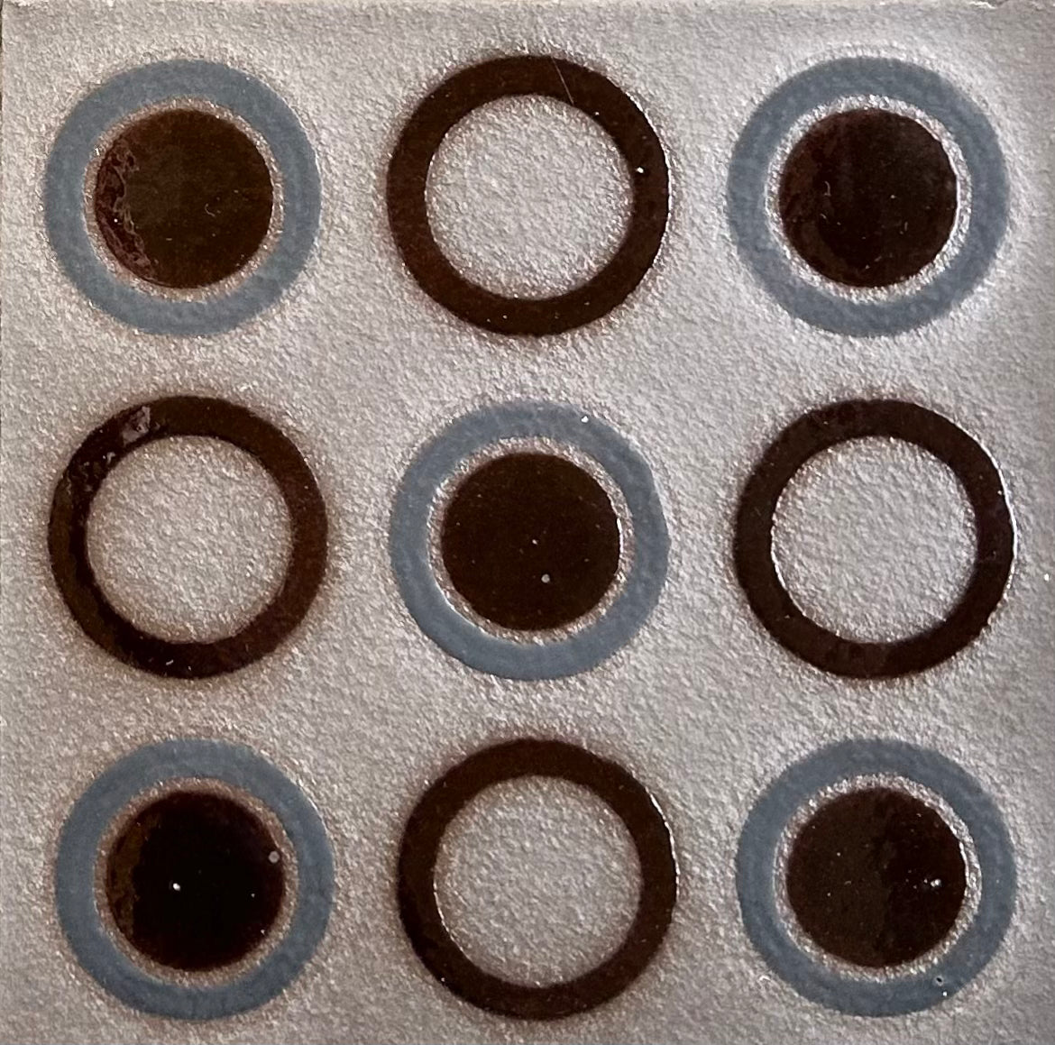 Circular glaze patterns on espresso colored ceramic tile